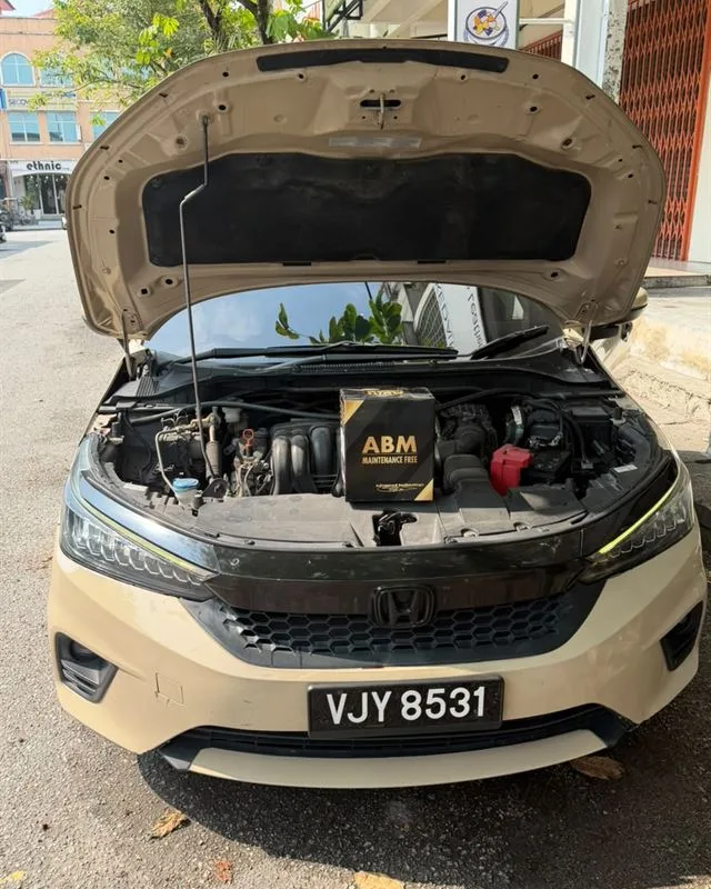 Beige Honda City with the bonnet open and a new ABM Maintenance Free battery box on the engine bay