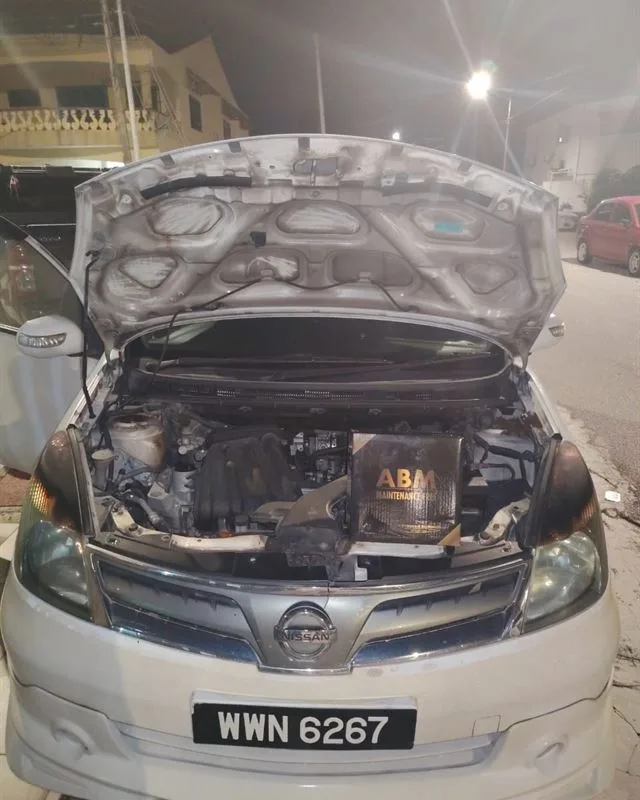 White Nissan Grand Livina at night with the bonnet open and an ABM Maintenance Free battery box on the engine