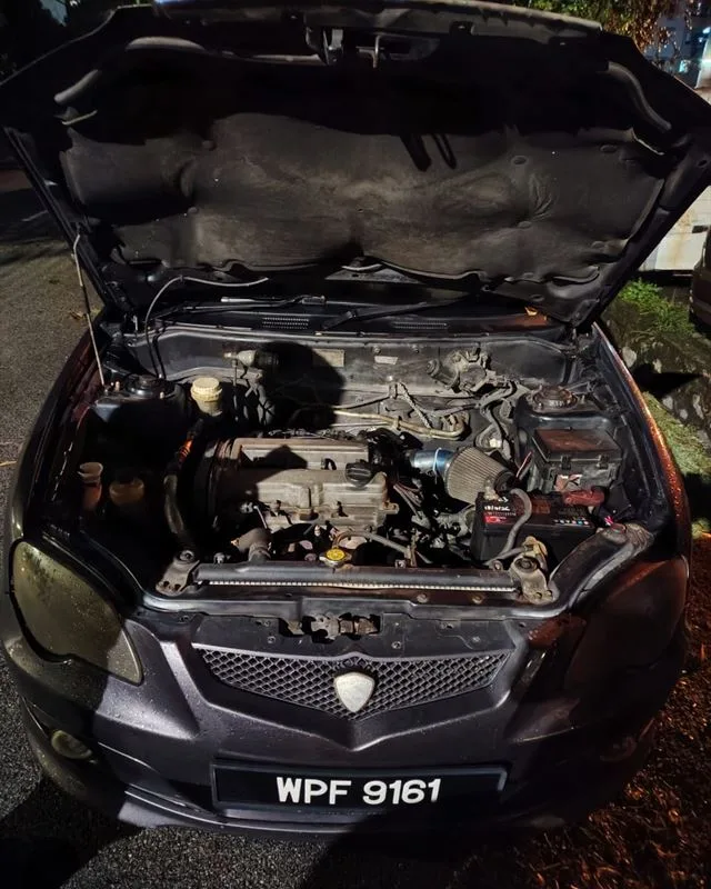 Dark Proton Waja at night with the bonnet open after an on-site battery replacement